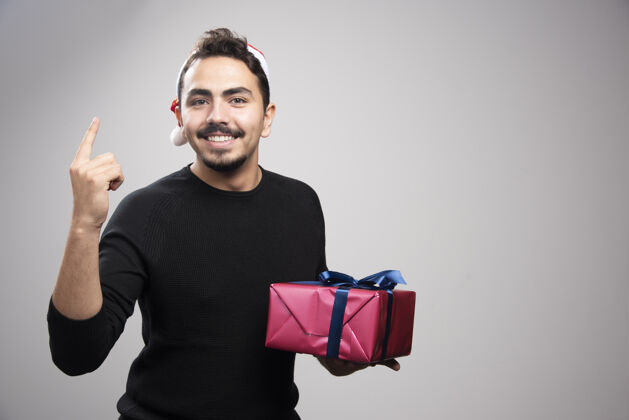 盒子一个年轻人拿着一个礼品盒在灰色的墙上礼物情感肖像