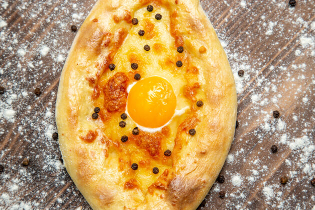 顶部顶视图新鲜的烤面包与煮熟的鸡蛋和面粉在棕色的桌子上面团烤鸡蛋面包包生的面包面粉