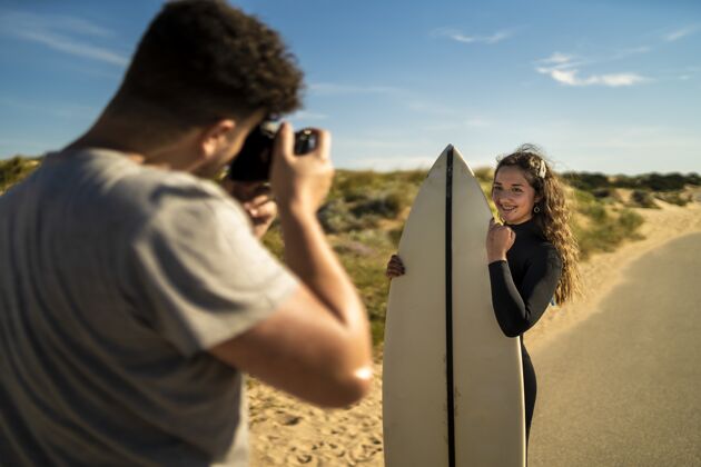 女人一位摄影师拿着冲浪板拍了一张迷人的女性照片度假高加索爱好