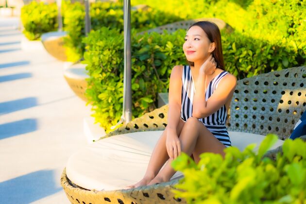 亚洲人肖像美丽的年轻女子放松微笑休闲度假酒店游泳池周围休闲海滩女士