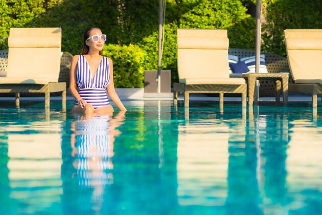 泳装肖像美丽的年轻女子放松微笑休闲度假酒店游泳池周围女性休闲度假村