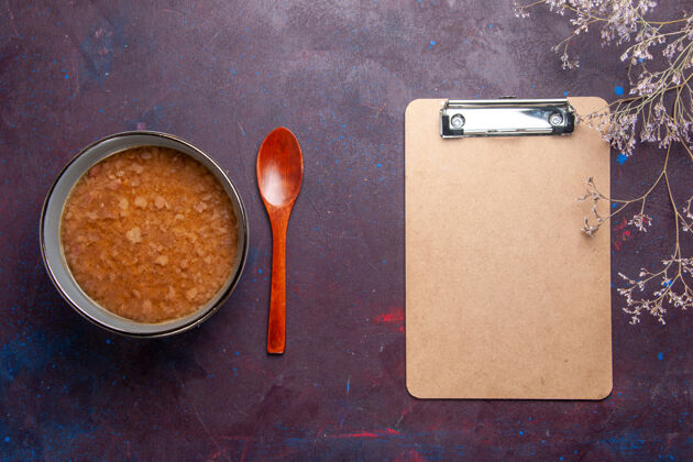 膳食顶视图褐色的汤在盘子里用记事本在深色的表面上汤蔬菜餐食物厨房油特纳蔬菜勺子
