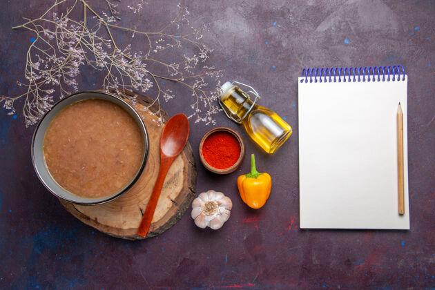 景俯视棕色的橄榄油汤笔记本和大蒜在黑暗的表面汤蔬菜餐食品菜豆油漆橄榄五颜六色