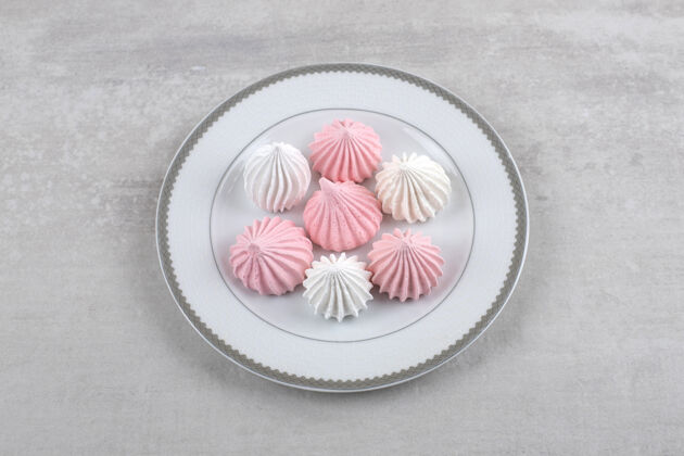 配料粉红色和白色的蛋白酥皮放在盘子里 放在大理石上卡路里零食盘子