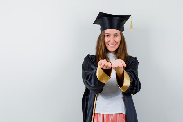 学院毕业的女人穿着休闲服 制服做接送手势 看起来很快乐 前视帽子给予制服