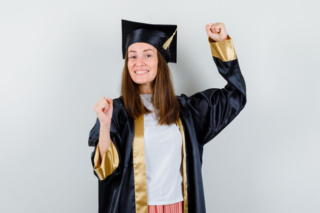 女毕业生穿着学院服展示获奖者的姿态 看起来很快乐正面图学术女性长袍