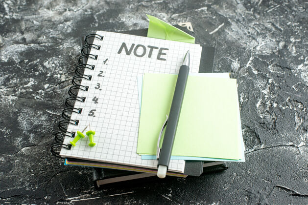 钢笔前视图打开记事本与笔和笔记写在灰色背景上工作纸张笔记