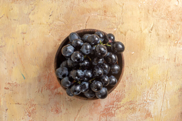 餐桌顶部特写查看葡萄奶油桌上一碗串的黑葡萄浆果黑色葡萄