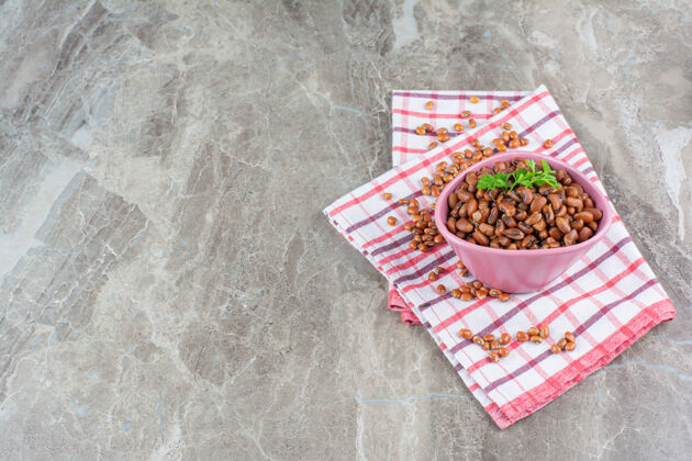 盐粉红色的煮豆子碗 大理石表面铺桌布蒸汽欧芹顶视图