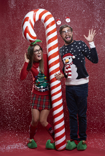 书呆子一对夫妇手持红白相间的圣诞手杖站着调情男人眼镜