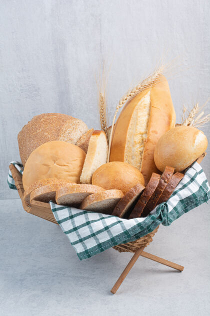 面包各式各样的面包放在大理石表面的篮子里食品面包切片