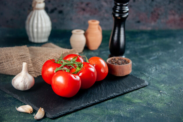 大蒜前视图新鲜的红色西红柿和大蒜在黑暗的背景沙拉西红柿蔬菜