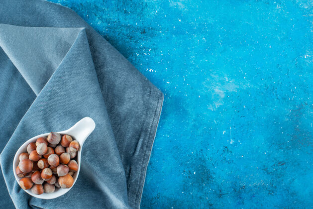 美味把榛子放在勺子里 放在蓝色表面的一块布上营养毛巾美味