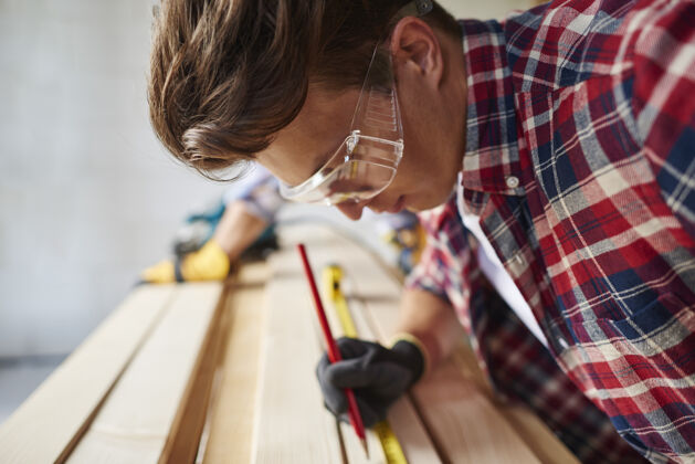 信心特写有经验的木匠和他的年轻雇员测量人设备