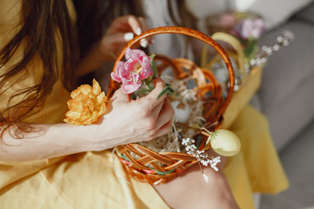 符号节日复活节篮子在一个穿着黄色衣服的女人手里油漆黄色颜色