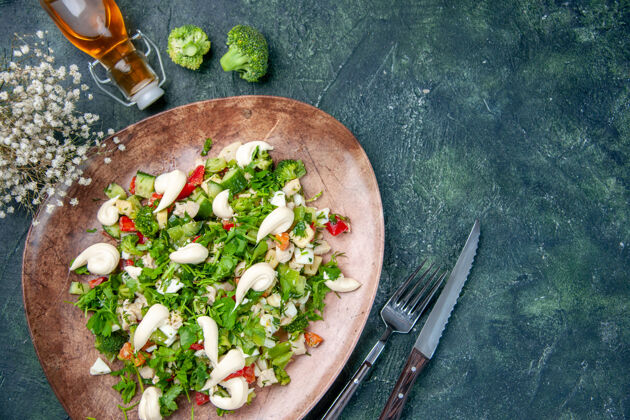 蓝色上图：新鲜蔬菜沙拉放在优雅的盘子里 餐具放在深蓝色的背景上沙拉正餐食物