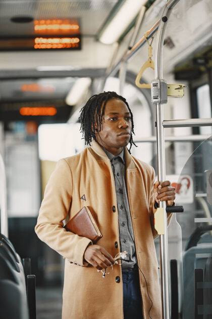 公共汽车一个非洲裔美国人坐在城市公共汽车上一个穿棕色外套的人一个拿着笔记本的人通勤成人棕色