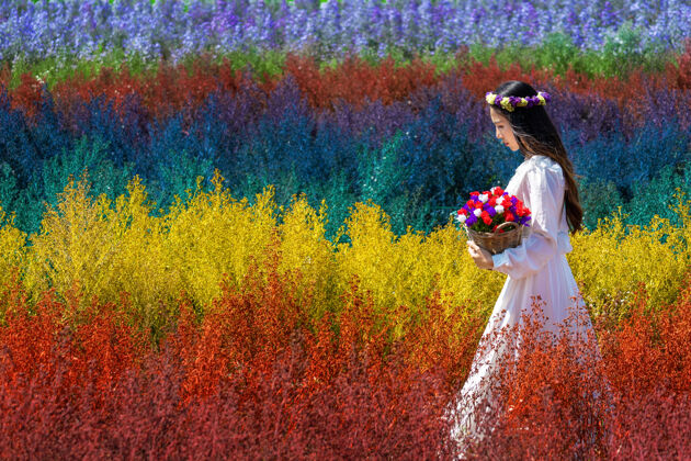 放松美丽的白衣女孩坐在彩虹花的田野里 清迈刀花园女士