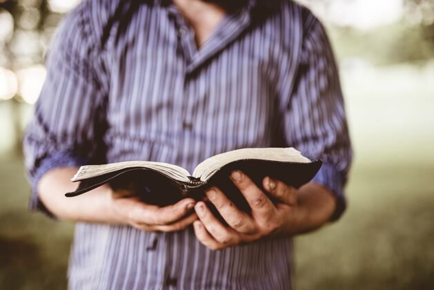 祈祷一个男人拿着一本打开的圣经 背景模糊的特写镜头信仰父亲男性