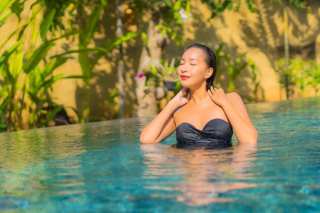 美丽美丽的亚洲年轻女子在游泳池里放松的画像水休闲热带