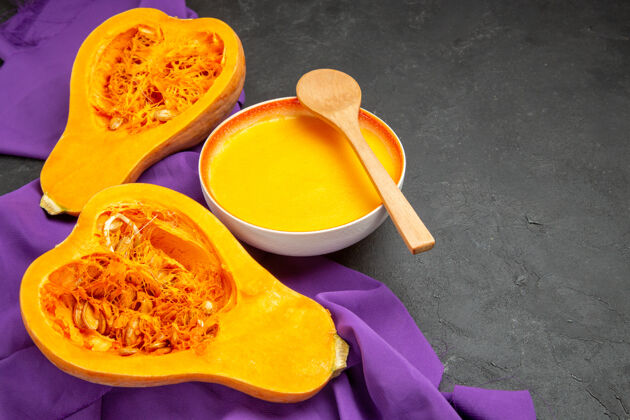 新鲜前视图简单的南瓜汤上紫色的纸巾和黑暗的餐桌用餐感恩节顺利冬南瓜食品健康