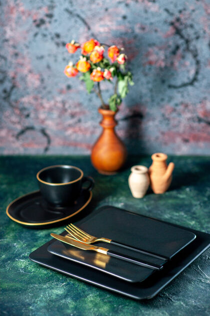 晚餐前视深色方形盘子 黑色桌子上有金色刀叉餐具餐厅午餐色盘子茶饮料托盘深色金色