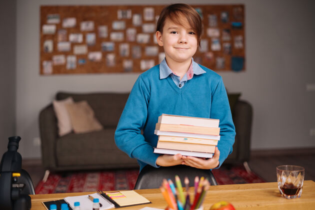 家庭学习一年级男生在家学习 手里拿着一堆书 准备上网上课束互联网科学