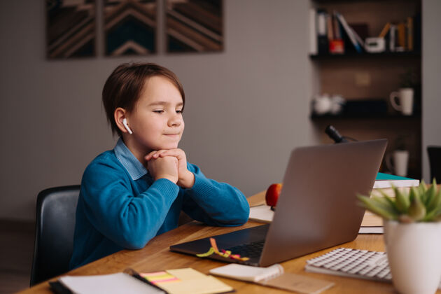 触摸一个未成年男孩用笔记本电脑在线上课耳机家庭学校做笔记