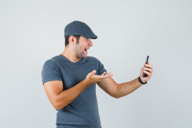 自信戴着t恤帽的年轻男子正在视频聊天 看上去很惊讶电子连接隔离接听电话