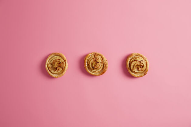 派水平拍摄新鲜自制的漩涡肉桂面包 粉红色背景甜食 诱惑和垃圾食品的概念美味的甜点打破饮食美味的甜卷自制粘性处理