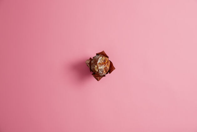 松饼在粉红色的背景上 用牛皮纸涂上糖粉的烤松饼新鲜的糖果 甜蜜的生活 垃圾食品的概念早餐美食家的甜点选择重点面包房早餐顶部