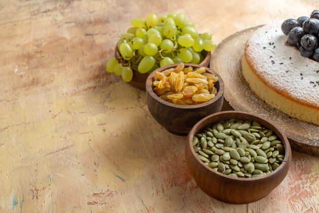 健康侧面特写图一个蛋糕一碗绿葡萄葡萄干南瓜籽一个蛋糕在黑板上南瓜食用坚果饮食