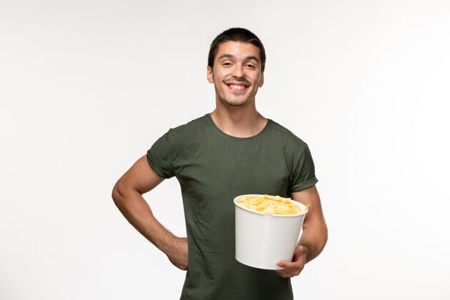 电影正面图身穿绿色t恤的年轻男性 在白色墙上微笑的土豆cips电影人男性孤独电影电影院咖啡电影杯子