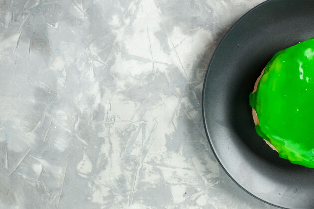 平底锅俯视图浅白色背景上绿色糖衣的小蛋糕蛋糕馅饼饼干甜甜的糖饼干饼干颜色小