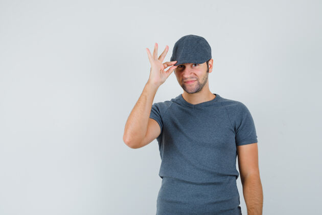 男孩一个年轻的男人戴着灰色t恤的帽子 看起来很优雅电脑网络摄像头远视兴奋的小