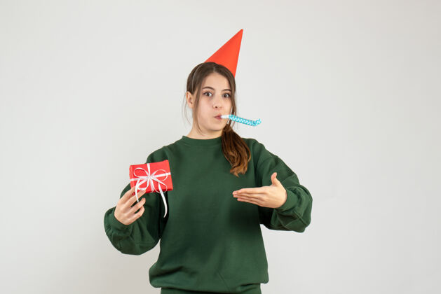 摩托板前视图困惑的女孩与党的帽子指着她的圣诞礼物使用噪音礼物指尖困惑女孩