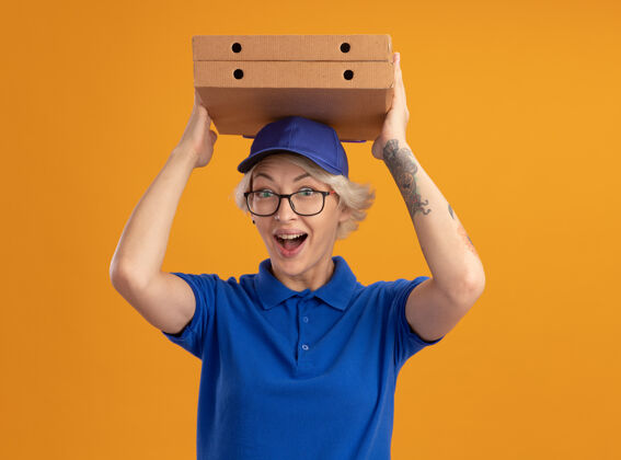 头身穿蓝色制服 戴着眼镜 头上抱着比萨饼盒 脸上挂着幸福笑容的年轻送货员年轻人女人送货