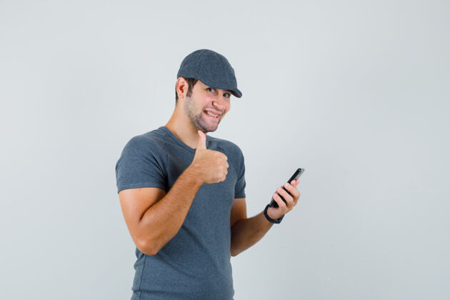 虚拟年轻男子手持手机 戴着t恤帽竖起大拇指 神采奕奕远视商务网络摄像头向上