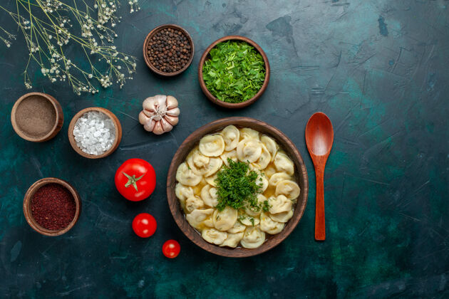 顶部俯瞰美味的饺子汤 用不同的调味料放在绿色的汤面上 食用肉食蔬菜面团午餐饺子盘子