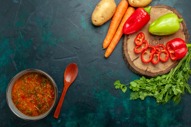 观点顶视图蔬菜汤与新鲜蔬菜对深绿色的背景材料汤餐食品蔬菜深绿色胡椒饮食