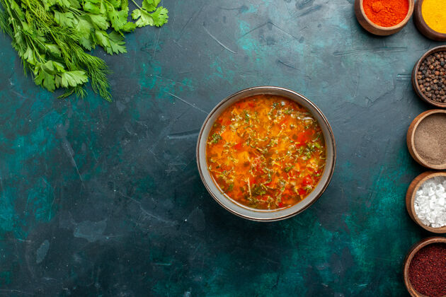 碗俯瞰美味的蔬菜汤 用不同的调味料放在深绿色的桌上 食物餐蔬菜配料汤产品蔬菜不同的晚餐