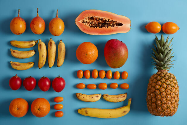 减肥蓝色背景上的新鲜异国水果菠萝 木瓜 香蕉 金橘 金钱草 维生素的来源夏季热带成分果汁或冰沙的水果食物概念平铺室内扁平一半