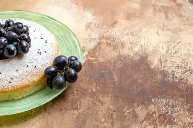 水果侧面特写镜头蛋糕一个开胃的蛋糕 盘子上有葡萄和糖粉壁板糖蓝莓