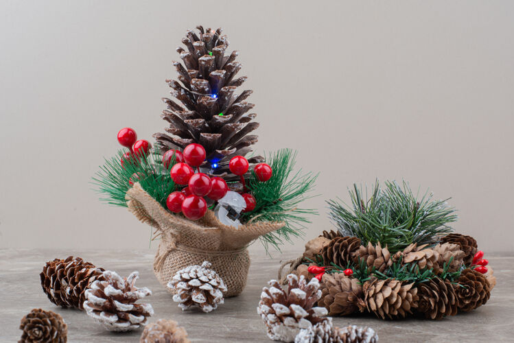 圣诞节用冬青浆果和树枝装饰的松果放在大理石桌上树枝冬天松树