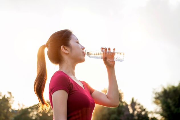 慢跑在阳光下喝水的运动型女人跑步早晨女人