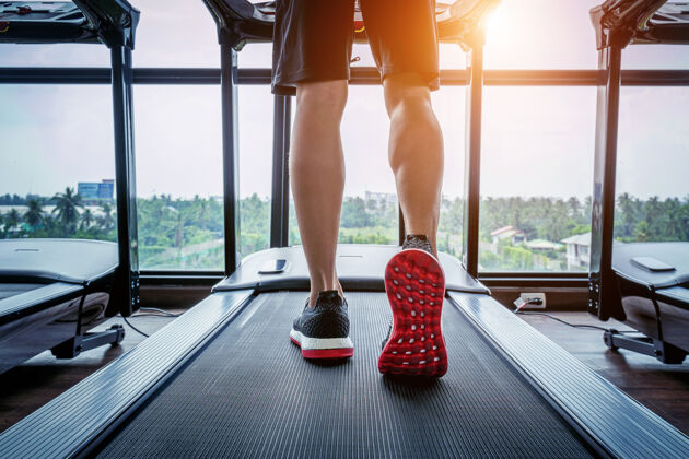 运动穿着运动鞋在健身房跑步机上跑步的男性脚运动概念教练运动鞋设备