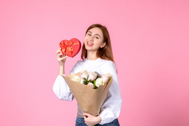 年轻女性正面图：年轻女性 带鲜花 作为女性节礼物 粉色背景 水平三月平等 爱性感女性约会 玫瑰女人花礼物花束