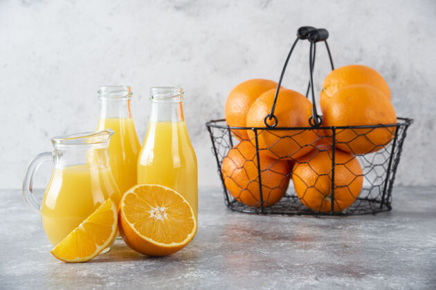 果汁石桌上放着一个装满多汁橙子的金属黑色篮子柑橘橙子异国情调