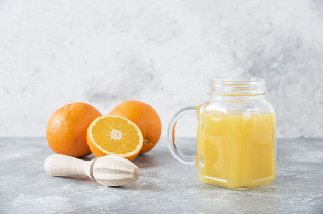 柑橘石桌上放着一杯果汁和新鲜的橙子成熟橙子异国情调