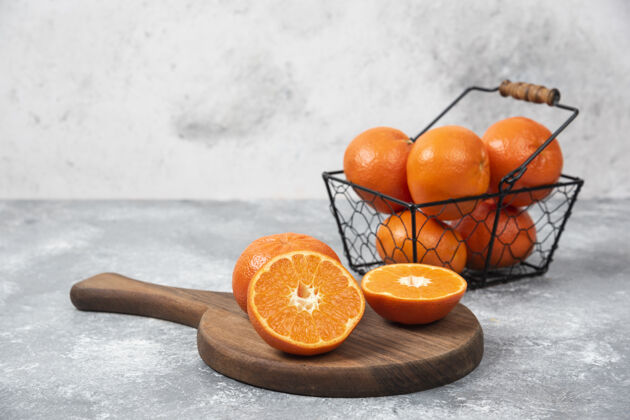 多汁石桌上放着一个装满多汁橙子的金属黑色篮子橙子提神热带